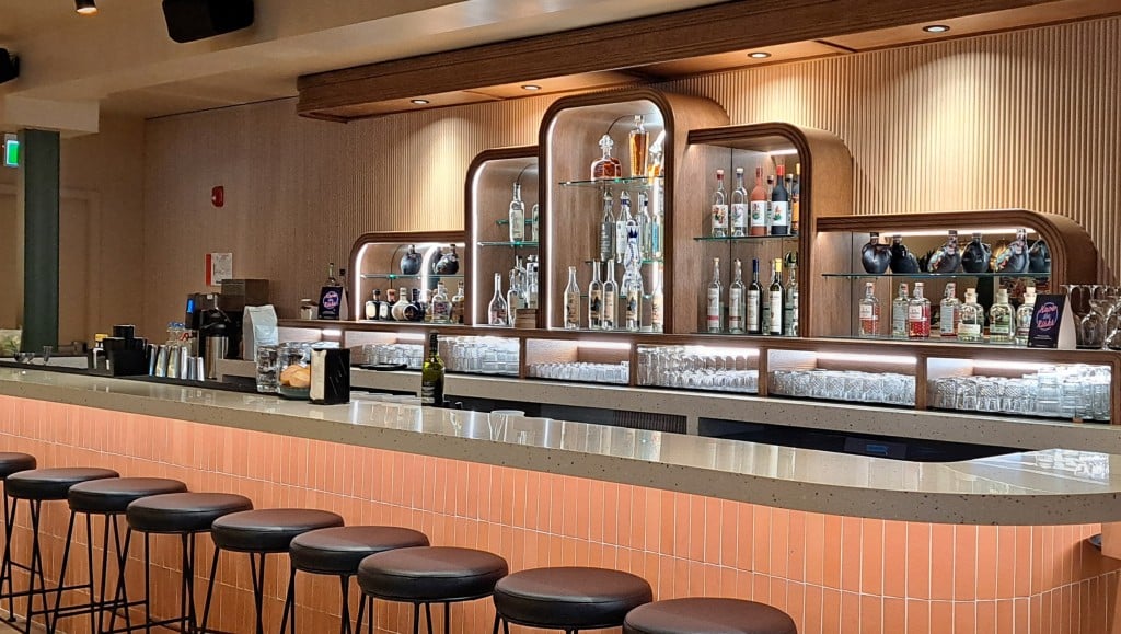 Cantina del Centro Revelstoke's bar with two staff working on either end of the long bar table. On the wall is a substantive collection of tequila and mezcal bottles.