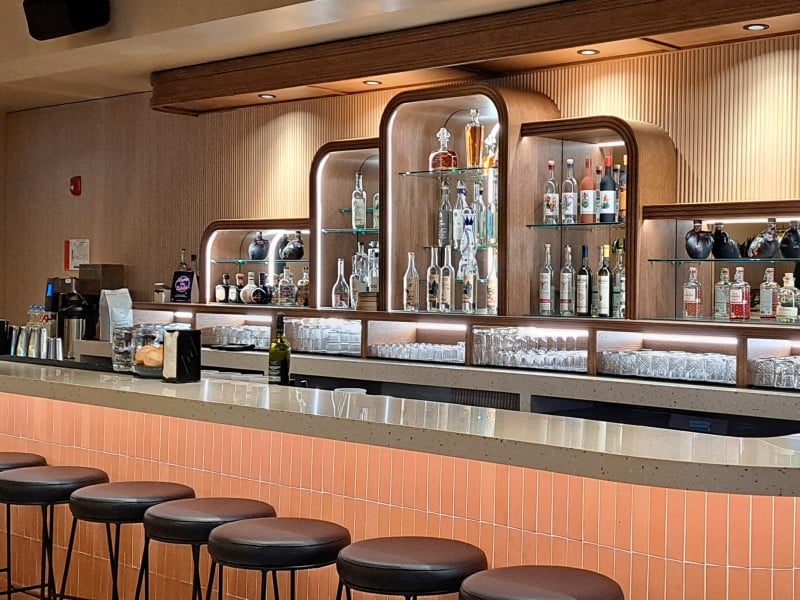 Cantina del Centro Revelstoke's bar with two staff working on either end of the long bar table. On the wall is a substantive collection of tequila and mezcal bottles.