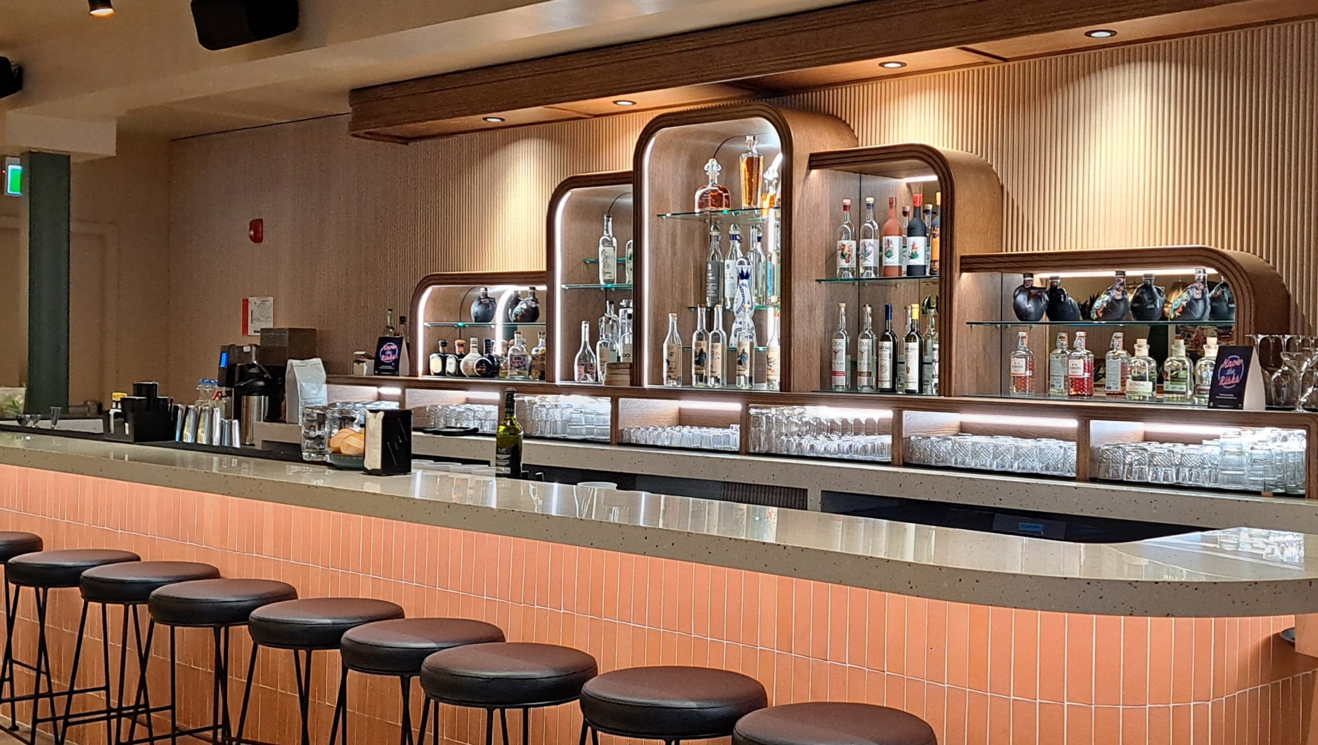Cantina del Centro Revelstoke's bar with two staff working on either end of the long bar table. On the wall is a substantive collection of tequila and mezcal bottles.