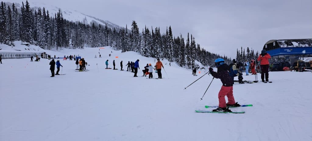 A panorama shot of guests at Revelstoke Mountain Resort Locals Day with skiers and snowboarders spread out on a sloped hill.