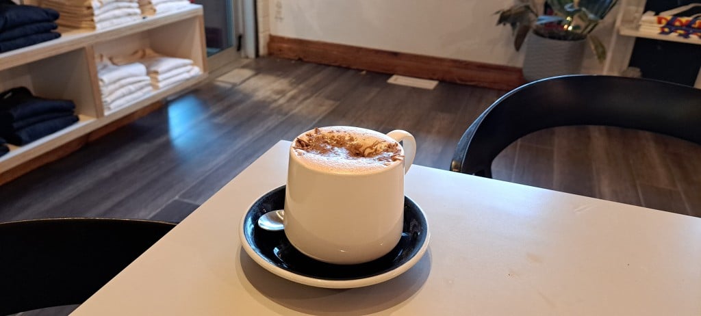 Revelstoke winter drink Diablo hot chocolate from Dose Coffee, a creamy drink in a white mug with chocolate sprinkles sinking into the foam