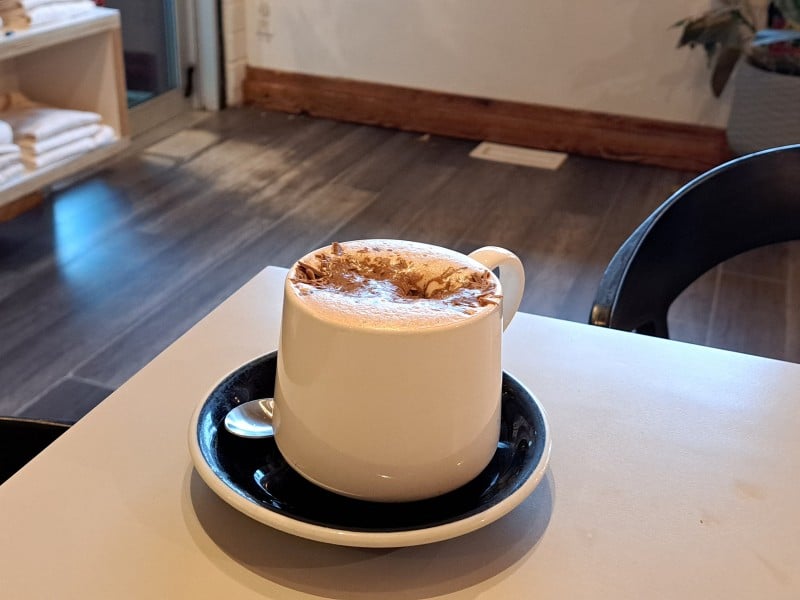 Revelstoke winter drink Diablo hot chocolate from Dose Coffee, a creamy drink in a white mug with chocolate sprinkles sinking into the foam