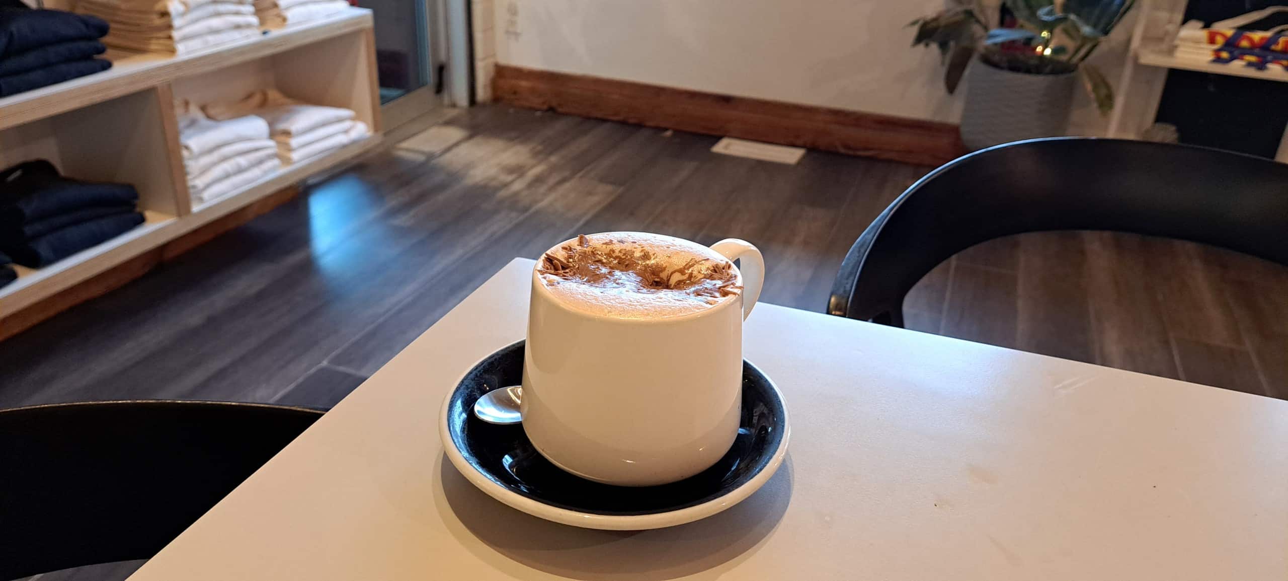 Revelstoke winter drink Diablo hot chocolate from Dose Coffee, a creamy drink in a white mug with chocolate sprinkles sinking into the foam