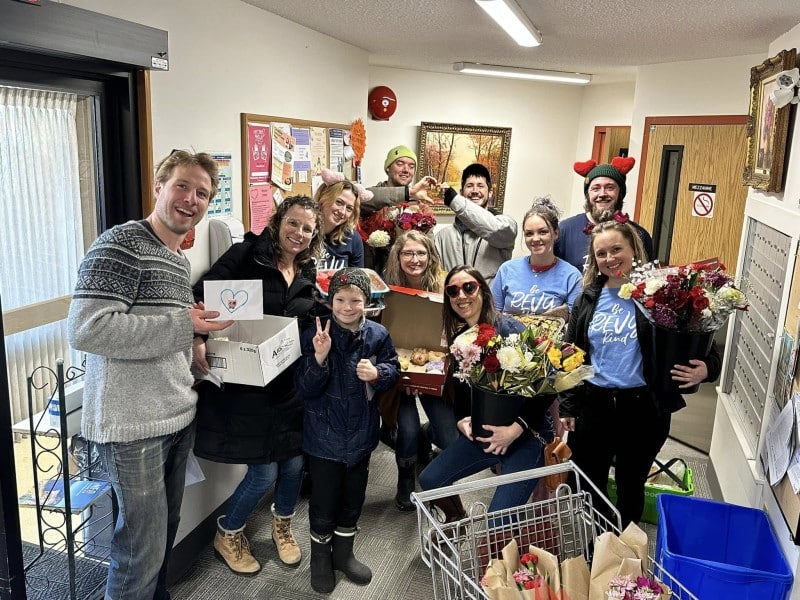 Revelstoke Unstuck volunteers and some residents of a local Senior's Assisted Living centre hold up the cards, flowers and baked goods made by the community.