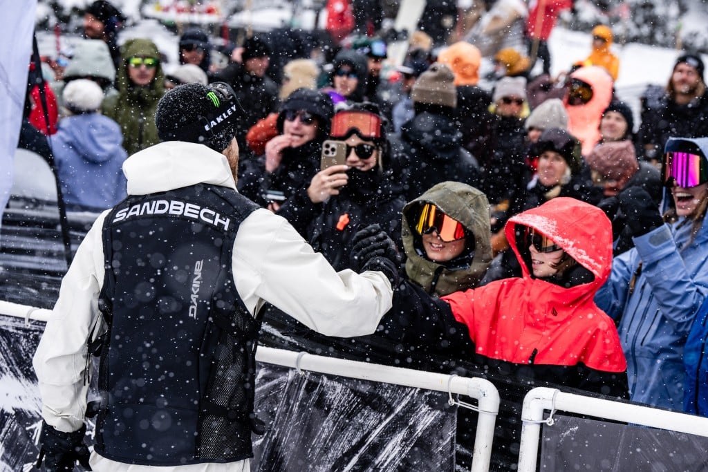 Ståle Sandbech, 2025 YETI Natural Selection Revelstoke winner high fives fans, all pressed up against a snow fence as he comes off the competition track.