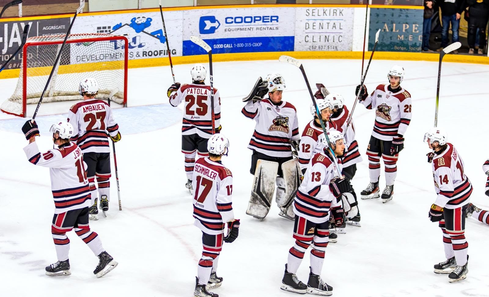 Revelstoke Grizzlies raise their sticks to the crowd while skating around the spot in front of the Revelstoke Grizzlies net.