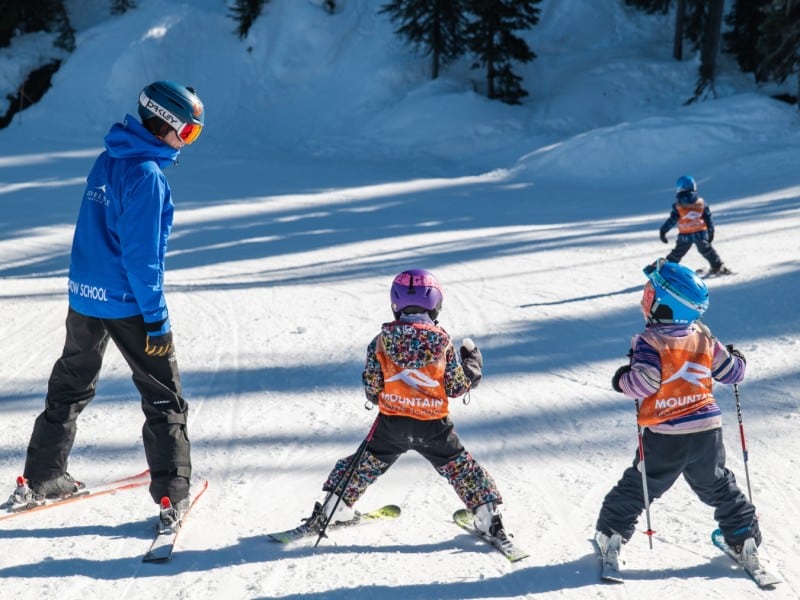 Two youth skiers and a coach head down a gently sloped hill during Revelstoke Mountain Resort 2024-2025 winter season lessons.