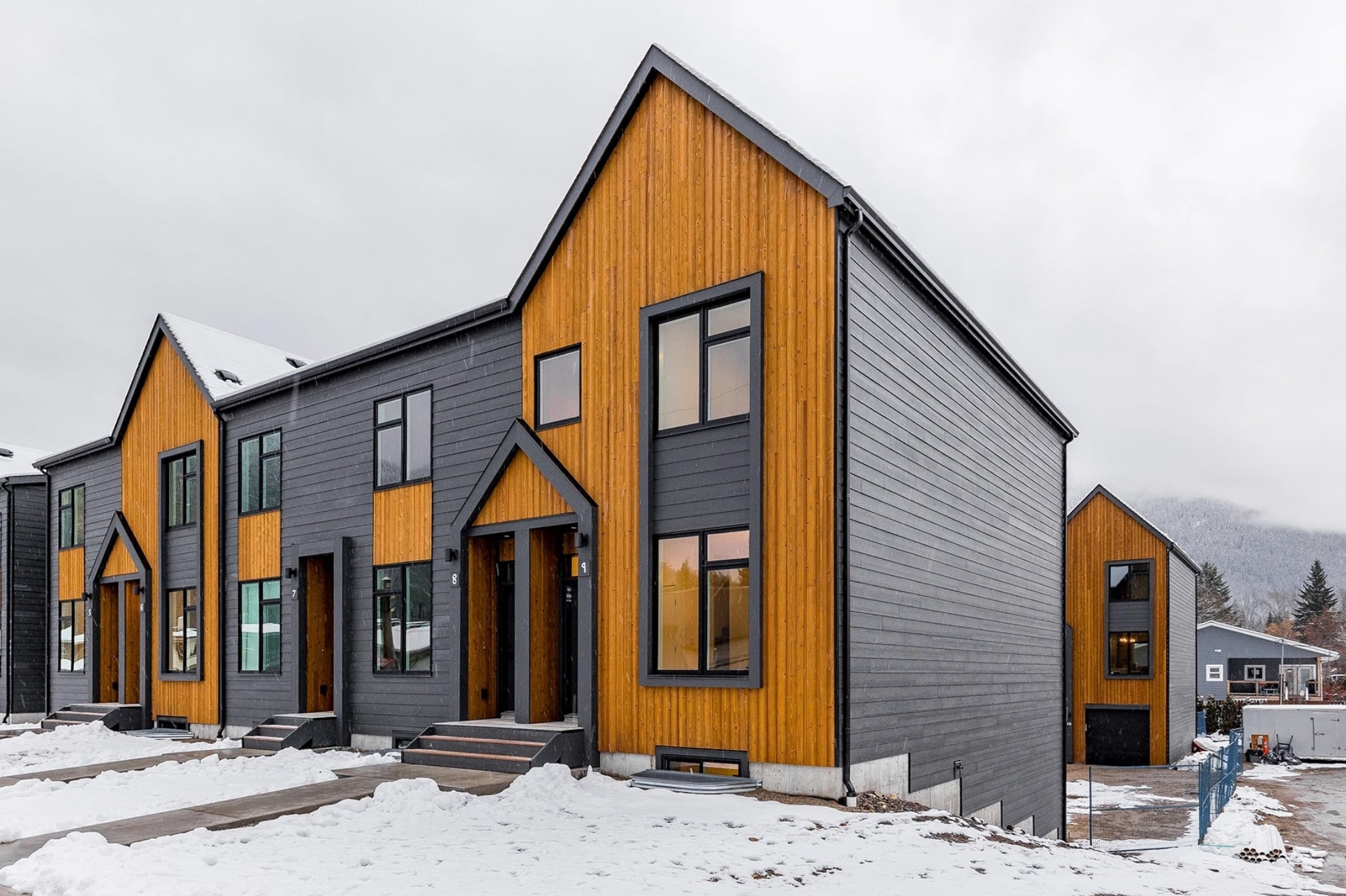 Boxfort Homes townhome, a row of two story side by side homes with wood accents and steel-grey metal siding.