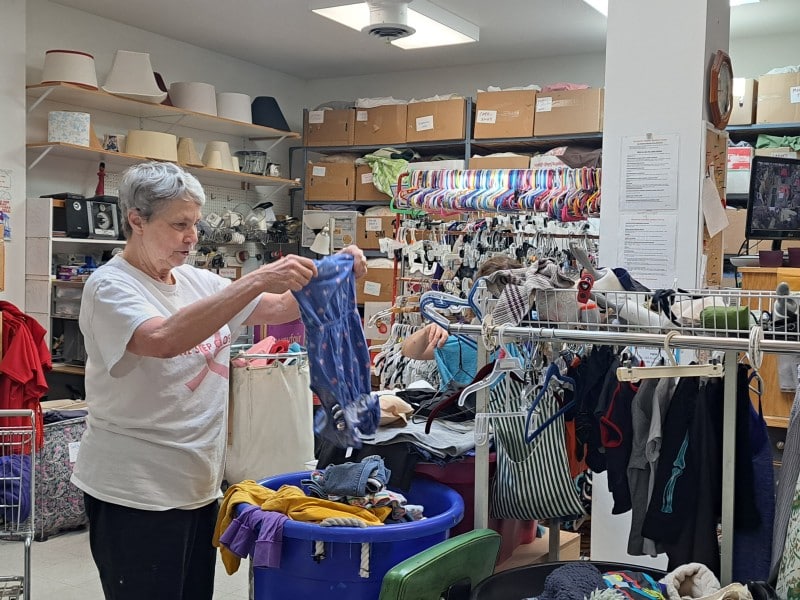 Cathy Thacker works through boxes of clothing recently donated to the Revelstoke Thrift Store. She is holding up a purple children's dress to make sure there are no rips, stains or missing parts.