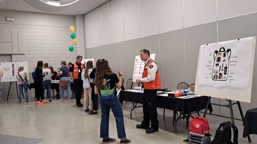 Revelstoke emergency preparedness town hall participants check out a poster showing what to put in a grab and go bag and also chat with the fire chief.