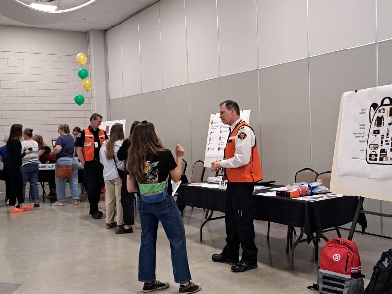 Revelstoke emergency preparedness town hall participants check out a poster showing what to put in a grab and go bag and also chat with the fire chief.