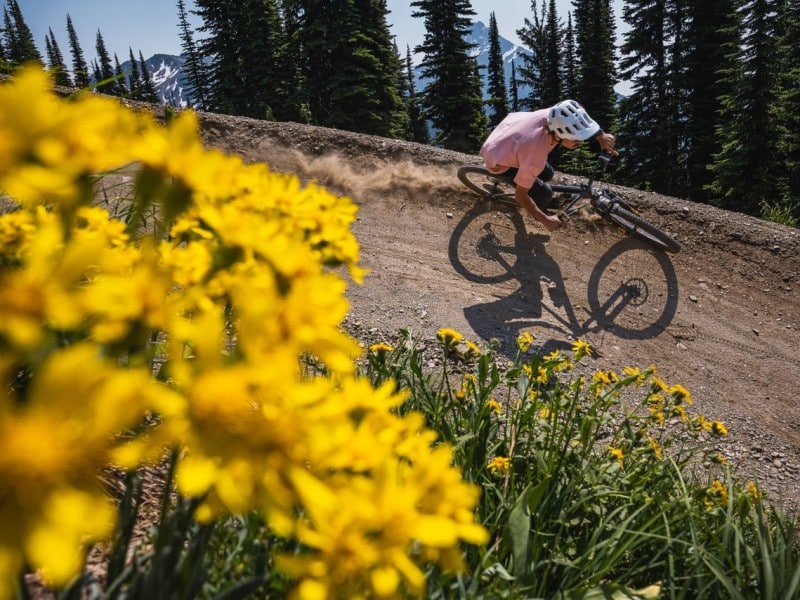 A Mountain bike rider rides down a sidewall on an alpine trail at Revelstoke Mountain Resort bike trail