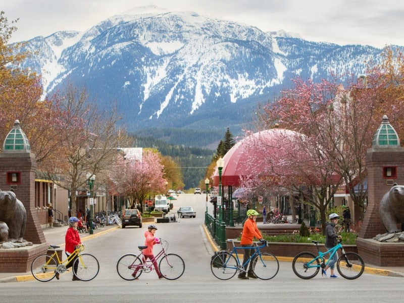 Go By Bike Week participants walk their bike across the street leading to Grizzly Plaza in Revelstoke