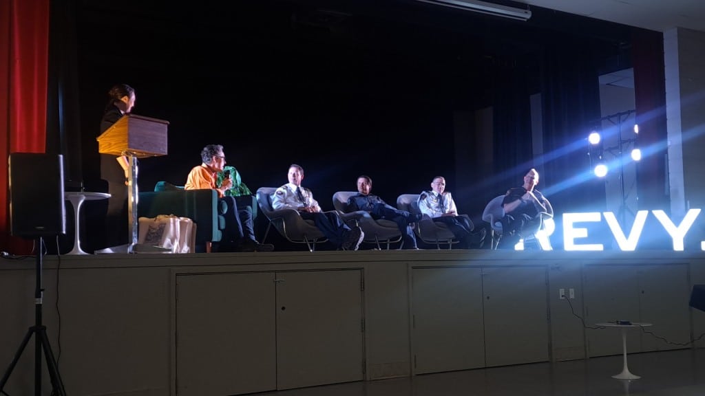 FireSmart panel sitting on a stage in a line, all holding microphones as they talk to the office.