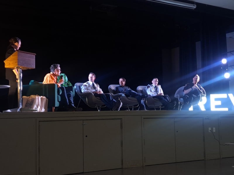 FireSmart panel sitting on a stage in a line, all holding microphones as they talk to the office.