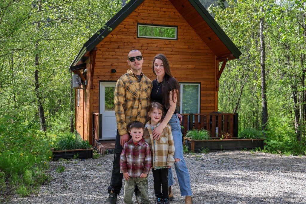 Alpha Mountain Lodging founders and their two children stand in front of one of their lodges