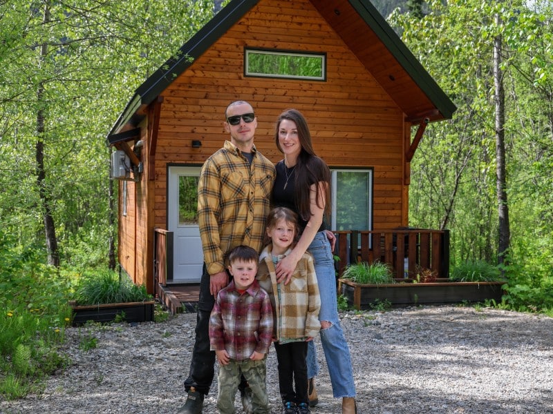 Alpha Mountain Lodging founders and their two children stand in front of one of their lodges