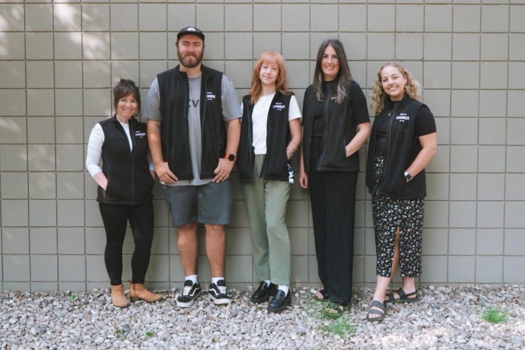 Revelstoke Chamber of Commerce team standing against a white painted prick wall.