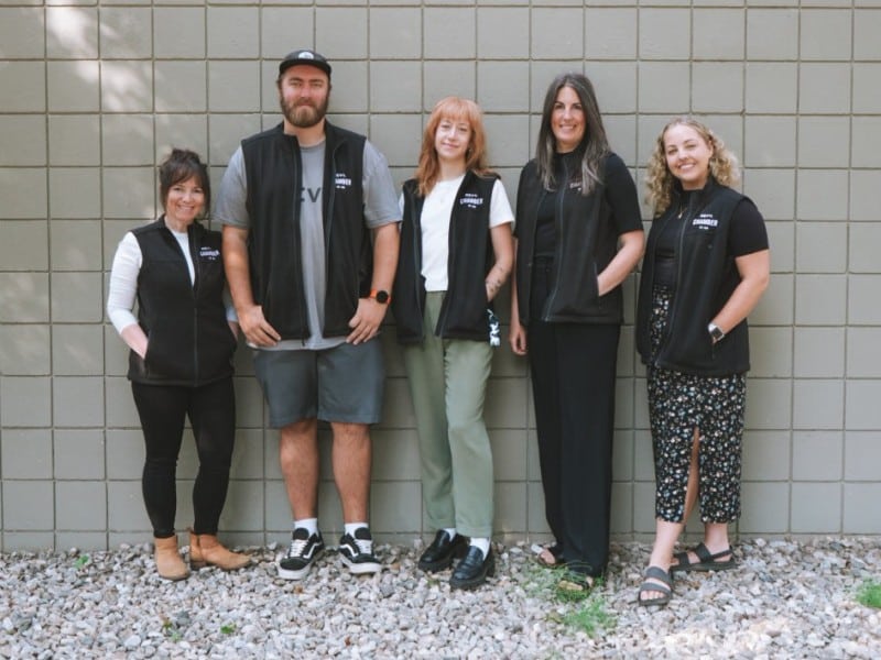 Revelstoke Chamber of Commerce team standing against a white painted prick wall.