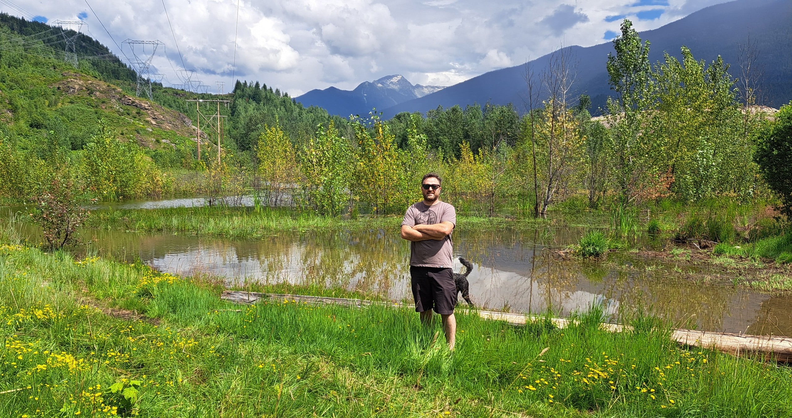 Liam Marshall stand in front of a sizable pond created by an out of frame beaver dam