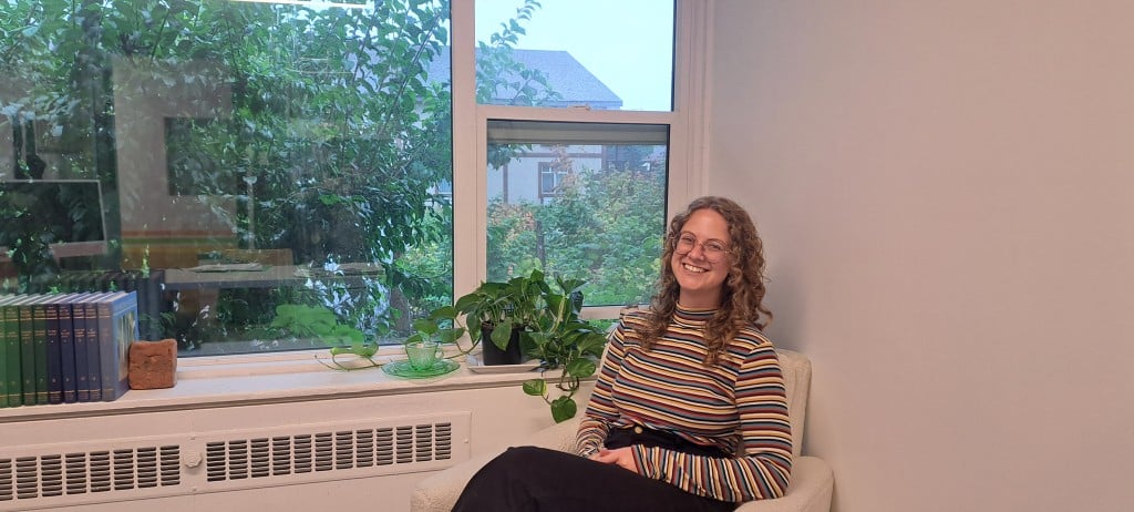 Taylor Sandell, Revelstoke Visual Arts director sitting in a chair in their office.
