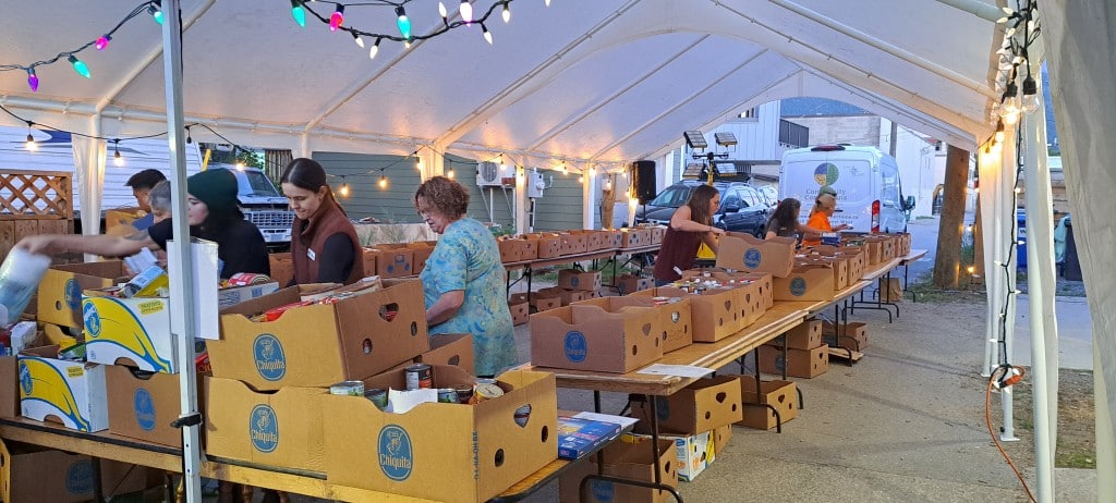 Emergency Service Food Drive volunteers sorting boxes of food under a large white tent