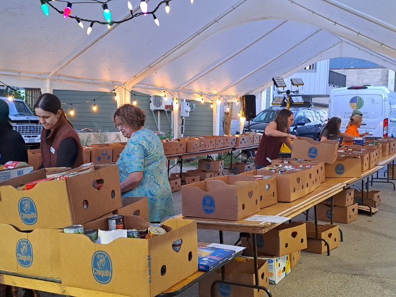 Emergency Service Food Drive volunteers sorting boxes of food under a large white tent