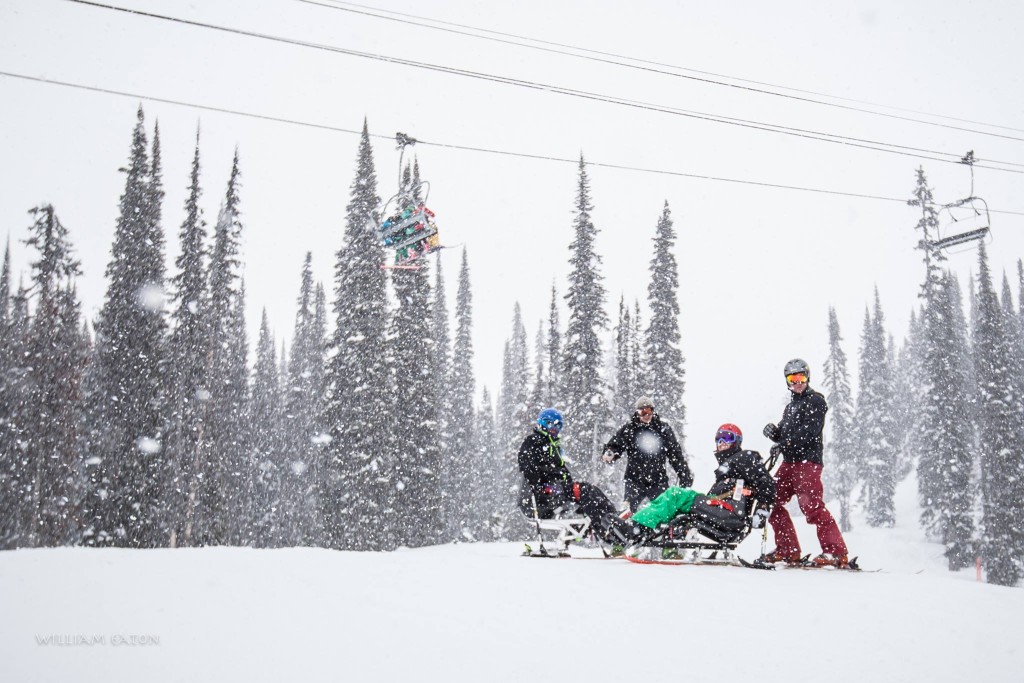Two Revelstoke Adaptive Sports Program sit ski participants and their coaches at the Revelstoke Mountain Resort under the Stoke chair.