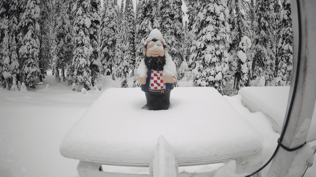 Revelstoke Mountain Resort opening day promotional photo of a garden gnome on a wooden platform with a couple of centimeters of snow around him.
