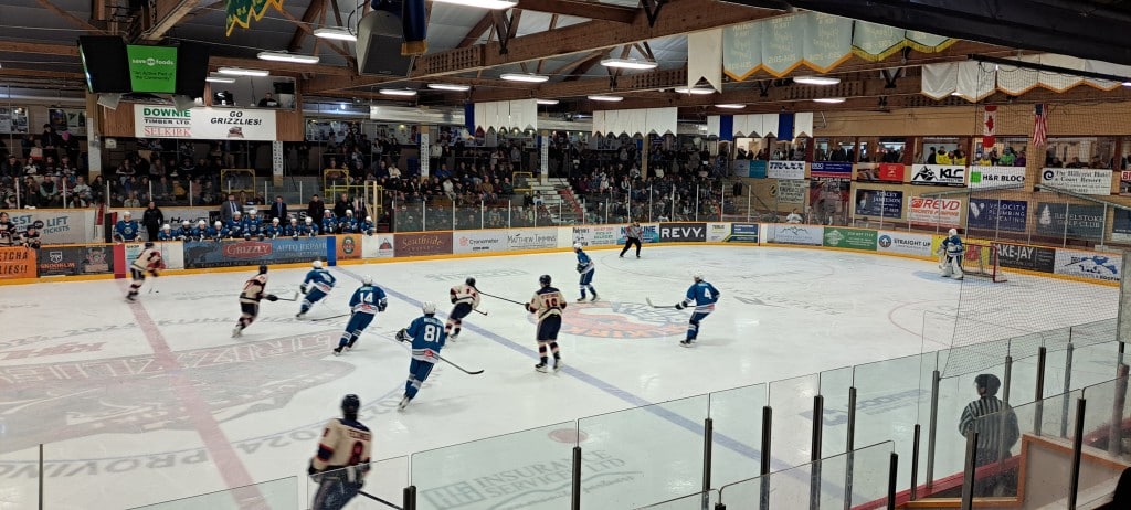 Wide shot of the Revelstoke Grizzlies New Year's Eve game against Kamloops Storm with the Grizzlies in their vintage blue jerseys. Players skating on the ice in the last minute of the game and many people in the stands