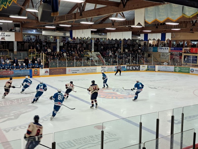Wide shot of the Revelstoke Grizzlies New Year's Eve game against Kamloops Storm with the Grizzlies in their vintage blue jerseys. Players skating on the ice in the last minute of the game and many people in the stands