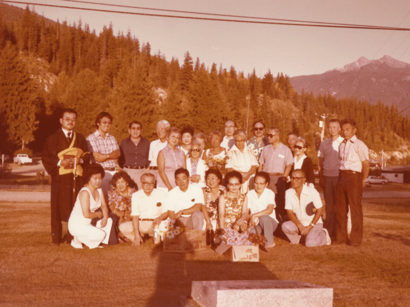 A sepia photo of Japanese Canadians gathered around a memorial at Revelstoke's Mountain View cemetery