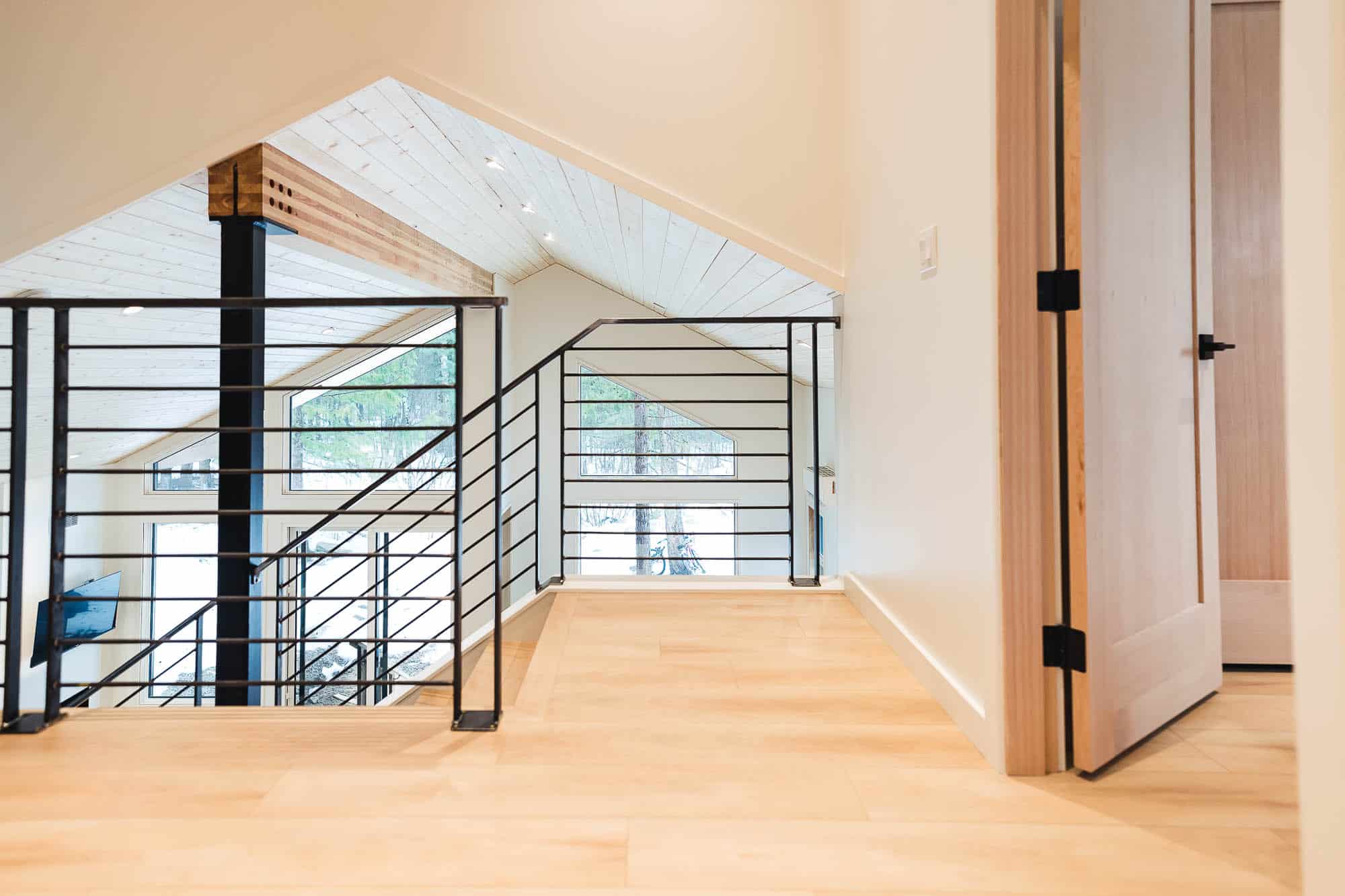 Monashees Drafting and Design interior shot of a large upper floor landing with wood floors, wood walls and wood ceiling. Windows are bringing in a lot of light from different angles