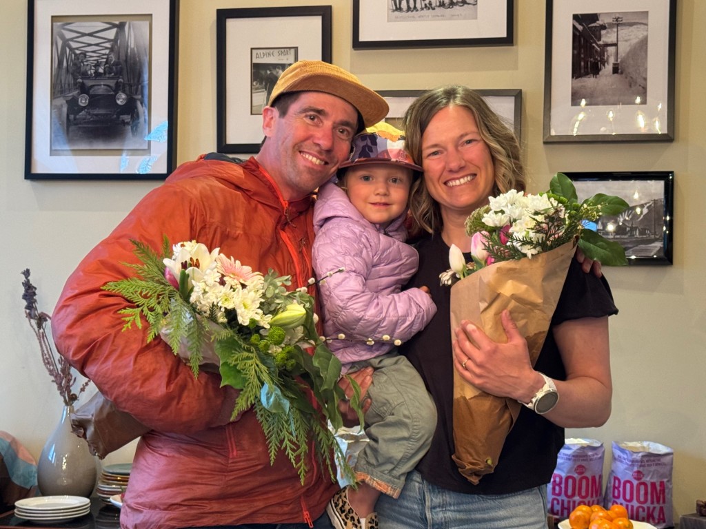 Jeff Mitchell, daughter Aspen and Rachel Reimer holding bouquets of flowers celebrating ten years of Open Mountains Project Society