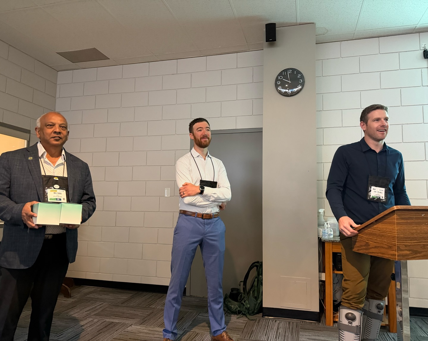 Three men standing at a podium presenting at SILGA 2026