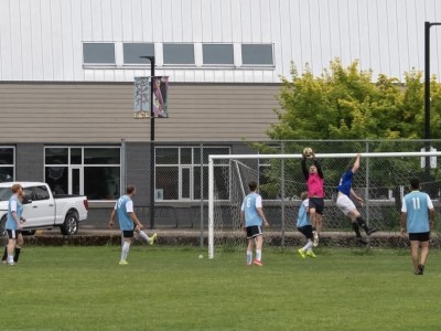 A collection of soccer players from the Revelstoke Drop-In Soccer Co-Ed Clash soccer tournament. all playing a game on the field.