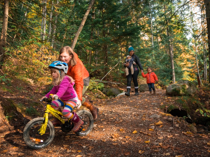 Family walking and biking on a Mount Revelstoke National Park path during the fall. Photo part of the Canada Strong Pass story.