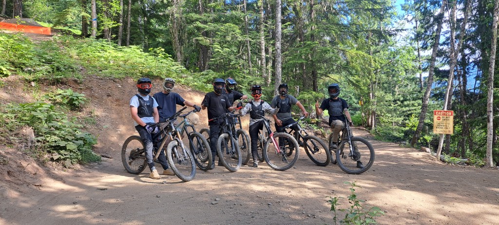 Bike riders on Salad Fingers trail at Revelstoke Mountain Resort. All are facing the camara, some are flashing a thumbs up.