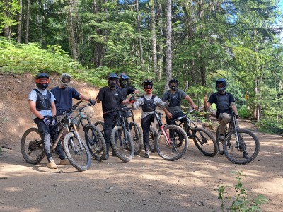 Bike riders on Salad Fingers trail at Revelstoke Mountain Resort. All are facing the camara, some are flashing a thumbs up.