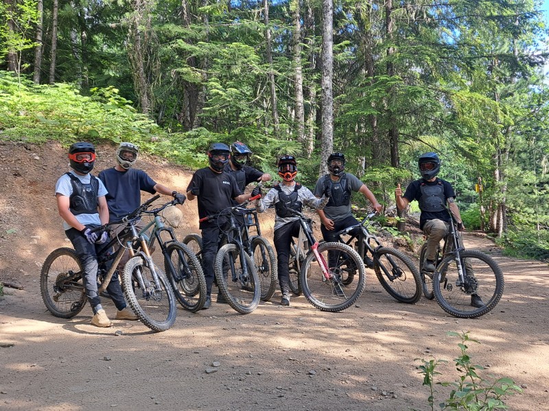 Bike riders on Salad Fingers trail at Revelstoke Mountain Resort. All are facing the camara, some are flashing a thumbs up.
