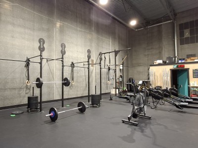 Interior shot of the CrossFit Revelstoke gym, home to the Revelstoke boxing club. general workout equiptment and weight racks are set up along the walls, the middle of the space has rowing machines and benches.