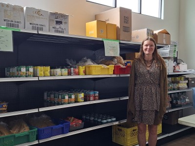 Jenna Thomsen Revelstoke Food Bank coordinator in front of Food Bank shelves