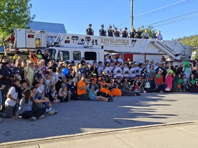 Volunteers crowd around a Revelstoke Fire Rescue Service fire engine. Everyone is cheering the countdown for the 2026 Emergency Service Food Drive